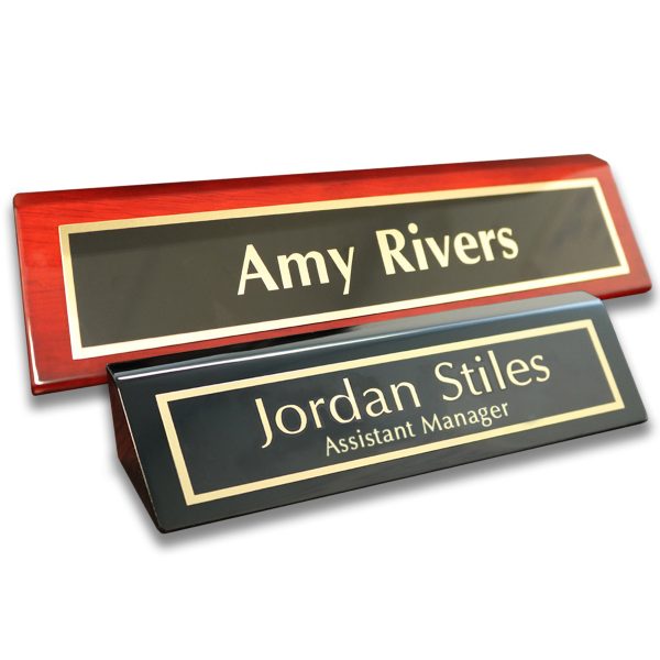 Piano finish desk wedges with metal name plates attached. Lines of text on red piano finish base and black piano finish base