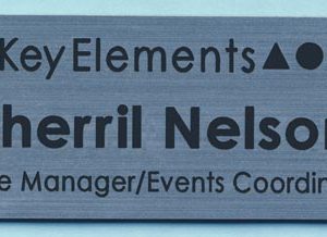 silver name tag with black engraved logo and text