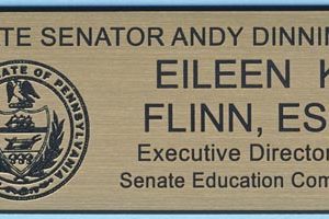 Gold metallic tag with black engraved PA state seal and text