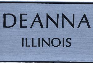 Silver name tag with engraved black text