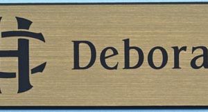 Gold name tag with black engraved logo and text