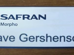 Silver engraved name tag with blue logo and text
