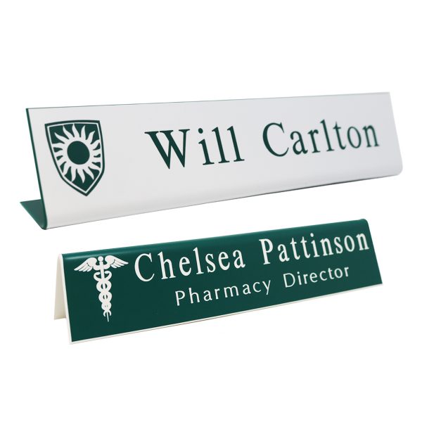 L-shaped name plates with engraved logo and text lines. White background with green engraving and green background with white engraving.
