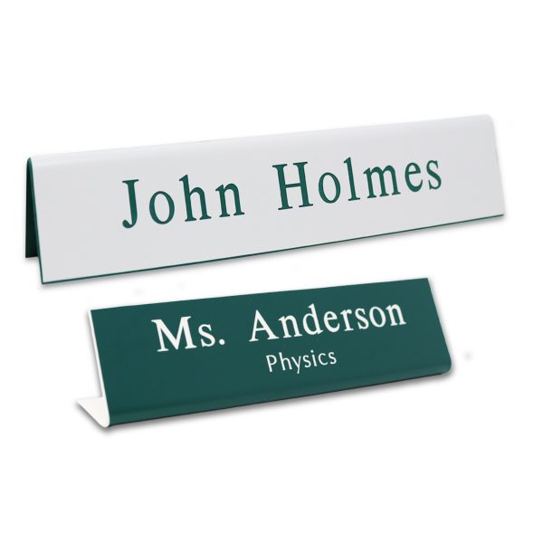 L-shaped name plates with engraved text lines. White background with green engraving and green background with white engraving.