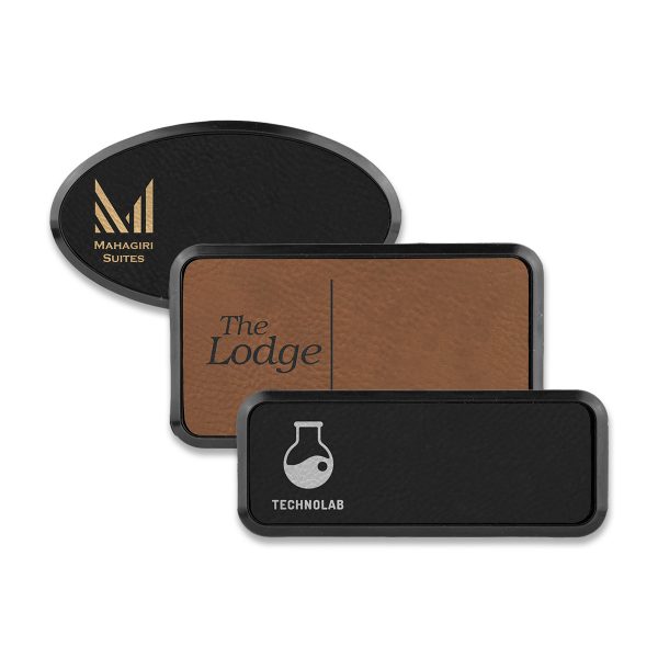 Framed rectangle and oval brown and black leatherette name tags with engraved logos.