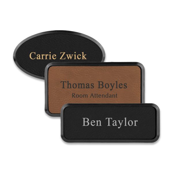 Framed rectangle and oval black and brown leather name tags with engraved lines of text