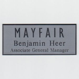 Silver engraved name tag with black logo and text